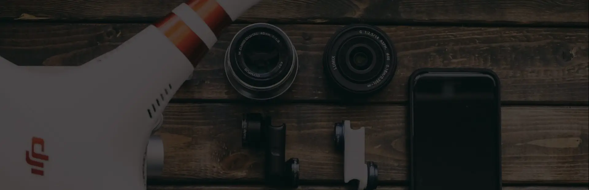 A sleek drone, interchangeable camera lenses, and a smartphone laid out on a rustic wooden surface for a tech review feature at BuildBrandsOnline.com.